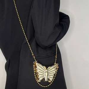 Elegant gold butterfly rhinestone mini crossbody bag with gold chain strap on black blazer