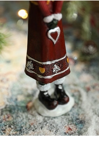 Detail of Christmas figurine featuring snowflake reliefs and heart accent on a resin robe