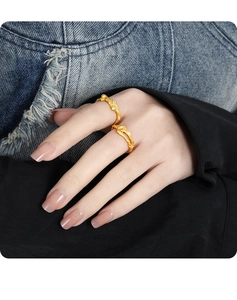 Macro detail of gold irregular texture rings with diamonds on hand over denim background
