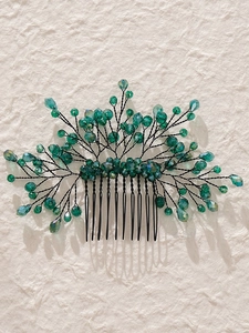 Detailed macro view of handmade bridal hair comb with green crystals and black alloy leaves