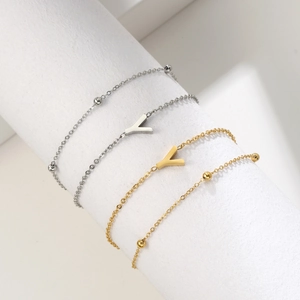 Detail of gold and silver double-layered stainless steel chains with a V pendant and beads