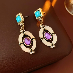 Detail view of vintage gold earrings with green turquoise and purple amethyst on leather