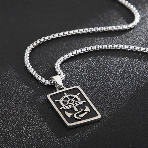 Détail du pendentif nautique argenté avec ancre et gouvernail gravés sur chaîne box