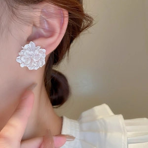 Close-up of white 3D flower stud earrings in resin with delicate multi-layered petals
