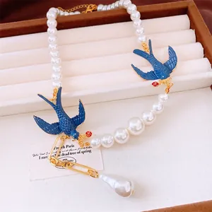 Elegant pearl necklace with blue enamel swallows and baroque pearl charm in a jewelry box