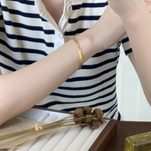 Close-up of golden S925 silver bracelet with hammered texture on a model wrist