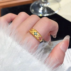 Macro detail of 24k gold-plated flower ring with brushed texture and colorful gems