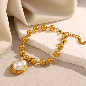Detail of 18K gold beaded bracelet with an irregular baroque pearl on textured stone