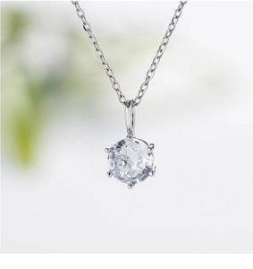 Macro view of silver six-prong pendant with clear round zircon on a cross chain