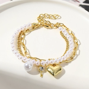 Detail view of multilayer gold chains with baroque pearls and heart key pendants