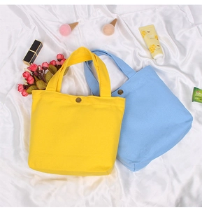 Close-up of simple yellow and blue canvas handbags with metallic buckle closures