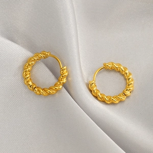 Elegant gold twisted hoop earrings on silk background with a vintage aesthetic