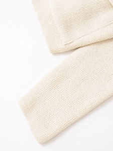 Dettaglio macro della trama in maglia grossa color crema e del motivo di tessitura
