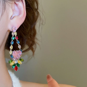 Detail of long heart-shaped earrings with multi-color zircon stones worn by a model