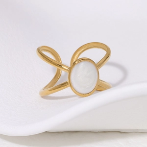 Detailed view of 18K gold plated cross ring with white oval shell inlay on textured base
