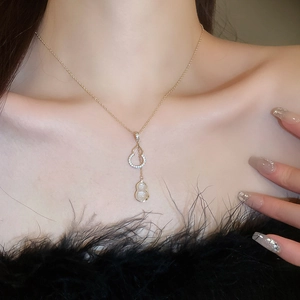 Détail du pendentif gourde plaqué or avec jade blanc et cristaux porté par le mannequin