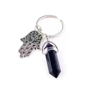 Detailed macro view of silver Hamsa hand charm and blue sandstone hexagonal crystal point