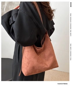Close-up of a large brown suede tote bag carried on shoulder, showing soft texture