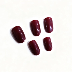 Faux ongles ovales rouge cerise brillants montrant la finition lisse sur fond blanc