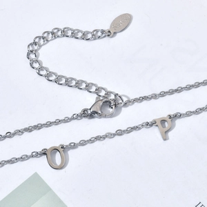 Macro detail of stainless steel necklace showing lobster clasp and initial pendants