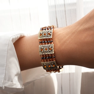 Detail of vintage bohemian bracelet with orange rhinestones and bronze beaded strands