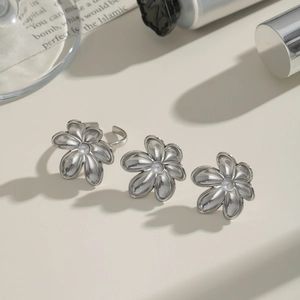 Elegant silver camellia jewelry set with white pearls on a minimalist background