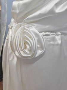 Dettaglio macro di un grande fiore in raso fatto a mano su un abito bianco di seta