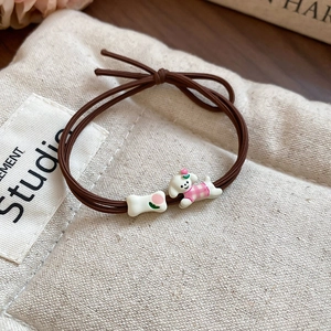 Detailed macro view of a cute cartoon puppy and bone charm on a brown elastic hair tie