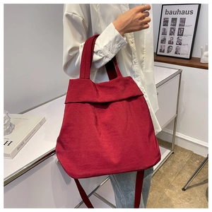 Deep red corduroy tote bag worn by a model in a minimalist home interior setting