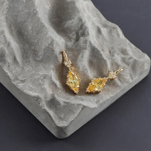 Macro shot of 18k gold plated earrings with marquise-cut yellow zircon and heart accent