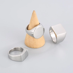Minimalist geometric stainless steel rings in circular and square shapes on wood stand