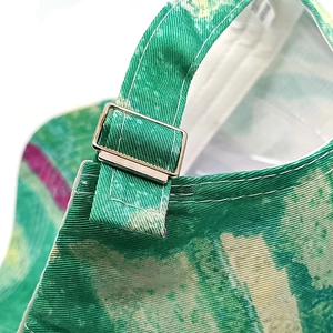 Detail of adjustable metal buckle and tie-dye canvas strap on the baseball cap