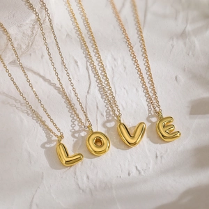 Collana dorata con ciondoli lettere L O V E su base bianca testurizzata elegante