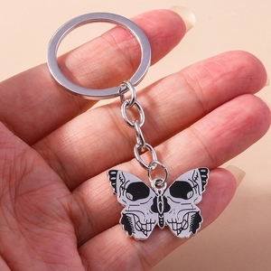 Close-up of gothic butterfly skull keychain with black and white enamel wings on alloy base