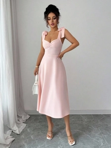Detail van roze mouwloze midi-jurk met schouderstrikken en elegante gedrapeerde stof