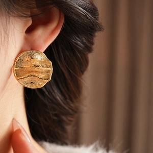 Vue détaillée de grandes boucles d'oreilles rondes plaquées or au design ondulé
