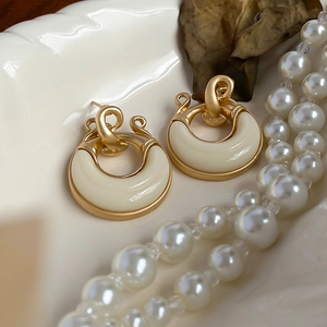 Dettaglio degli orecchini rotondi vintage in oro e resina crema su piatto bianco