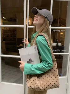 Beige polka dot canvas tote bag shown in a stylish casual outfit with a green shirt
