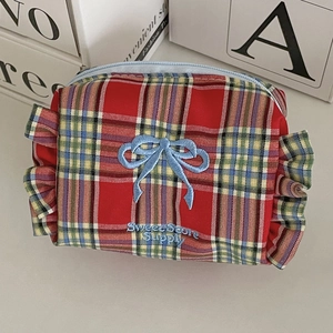 Detail der roten Karo-Kosmetiktasche mit blauer Schleifenstickerei und Rüschenrand