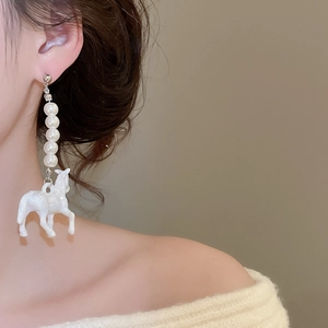Détail de la boucle d'oreille en perles avec pendentif cheval blanc portée par un mannequin