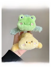 Close-up of cute plush hair claws featuring embroidered green frog and yellow duckling designs
