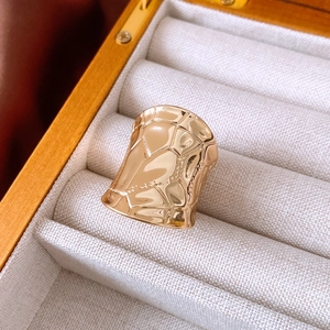 Detail of wide irregular gold ring with hammered texture in a wooden jewelry box