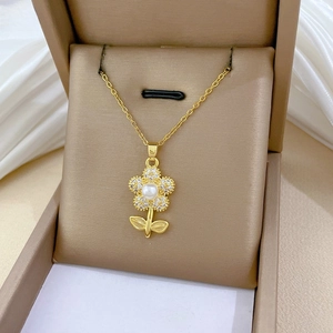 Detailed view of a gold floral necklace with crystals and pearl in a jewelry gift box