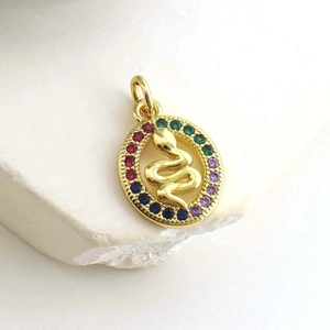 Macro detail of gold oval pendant featuring a snake relief and multi-color zircon inlay