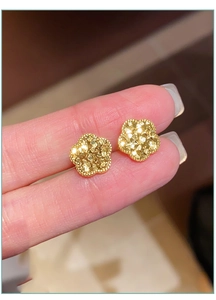 Detailansicht goldener Fünf-Blatt-Blütenohrringe mit strukturierter Schimmer-Optik