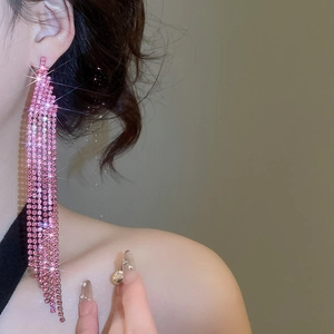 Macro detail of long sparkling pink rhinestone fringe earrings on a female model