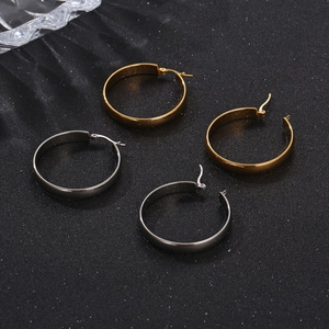 Polished gold and silver stainless steel hoop earrings on a textured black background