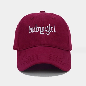 Dettaglio del ricamo bianco baby girl in stile gotico su cappellino in cotone bordeaux