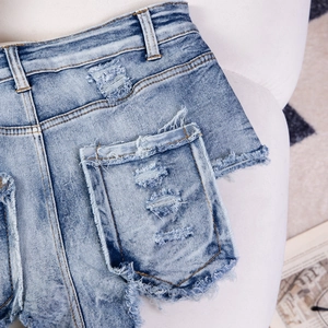 Dettaglio di pantaloncini di jeans con strappi su tasche posteriori e orlo sfrangiato