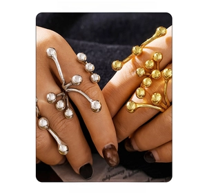 Close-up of golden and silver branch rings with metallic spheres on model fingers
